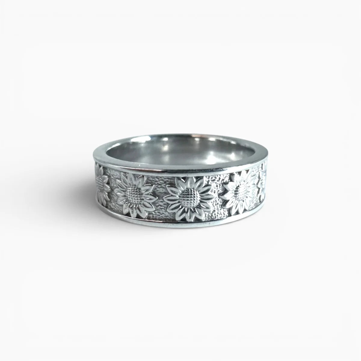 Gros plan sur la texture gravée de la bague Halo Solaire : pétales de tournesol polis contrastant avec l'argent brossé.