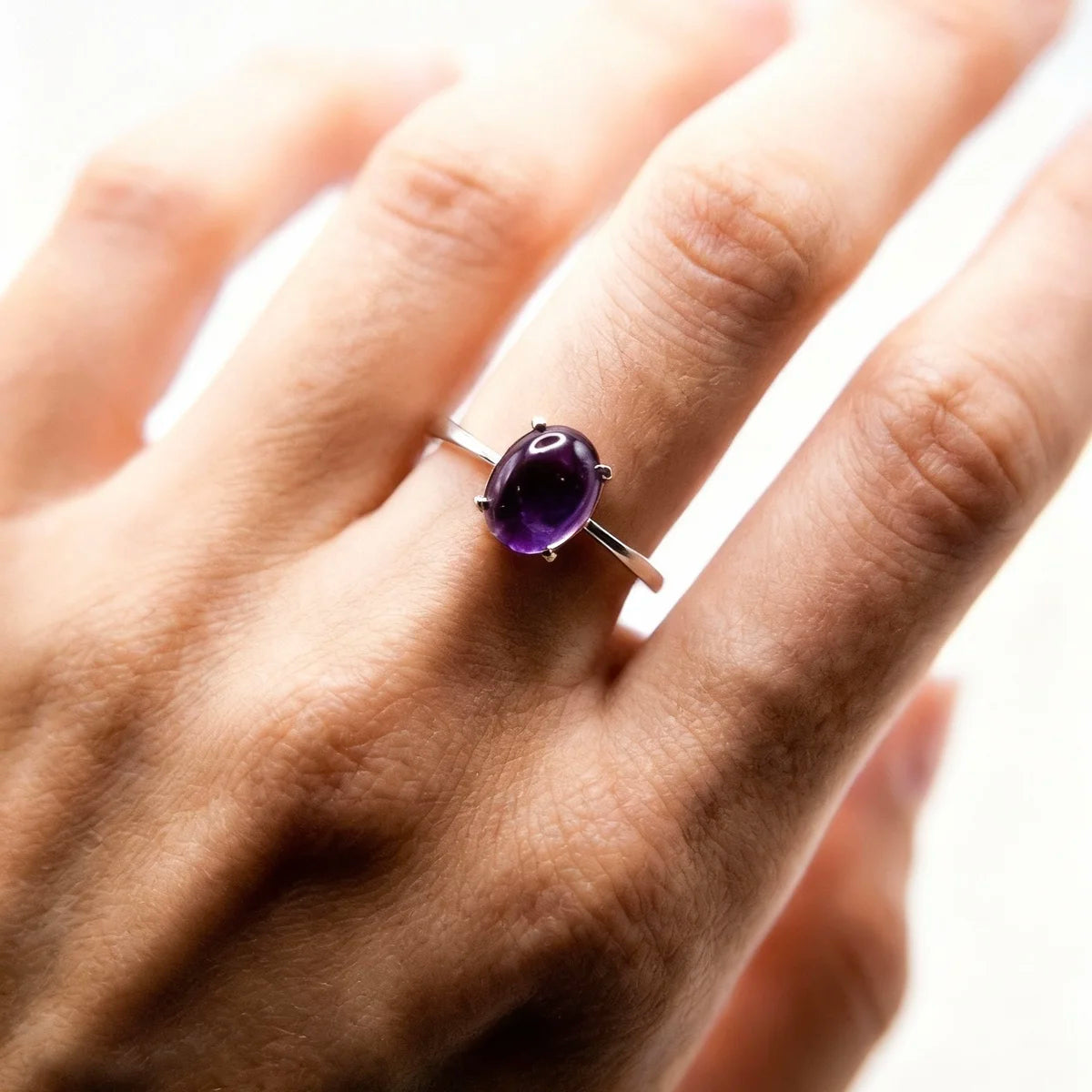 Détail du cabochon violet de la bague argent améthyste Aura, pierre lisse et naturelle, portée sur une main