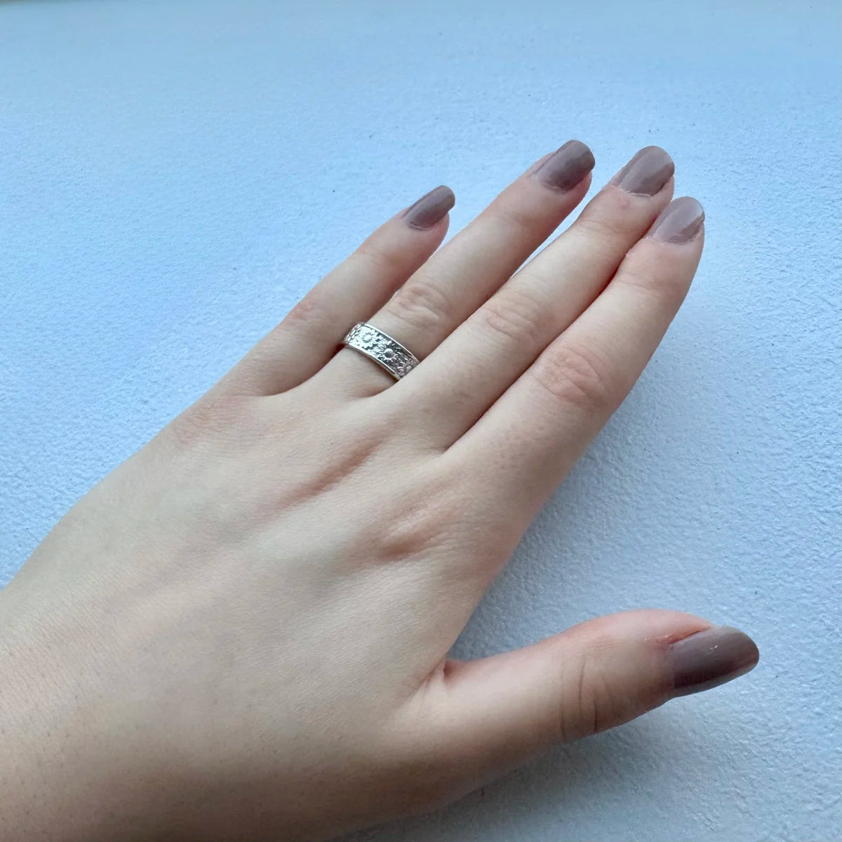 Bague anneau tournesol portée à l'annulaire, captant la lumière du soleil, symbole de joie et de vitalité.