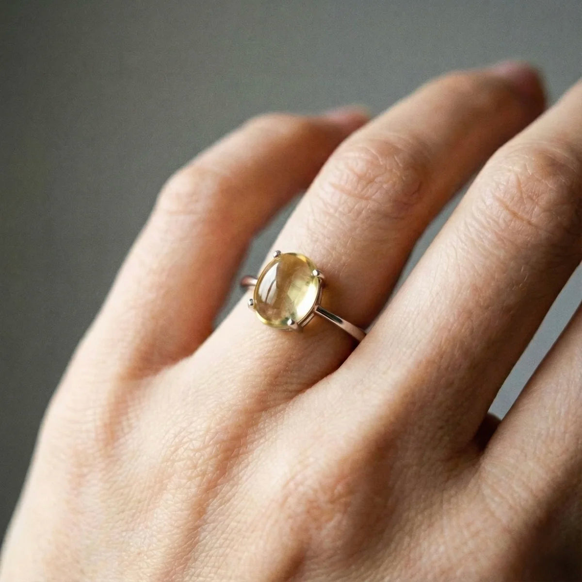 Détail de la citrine cabochon de la bague Aura portée à l'anunulaire, pierre transparente aux reflets jaunes naturels.