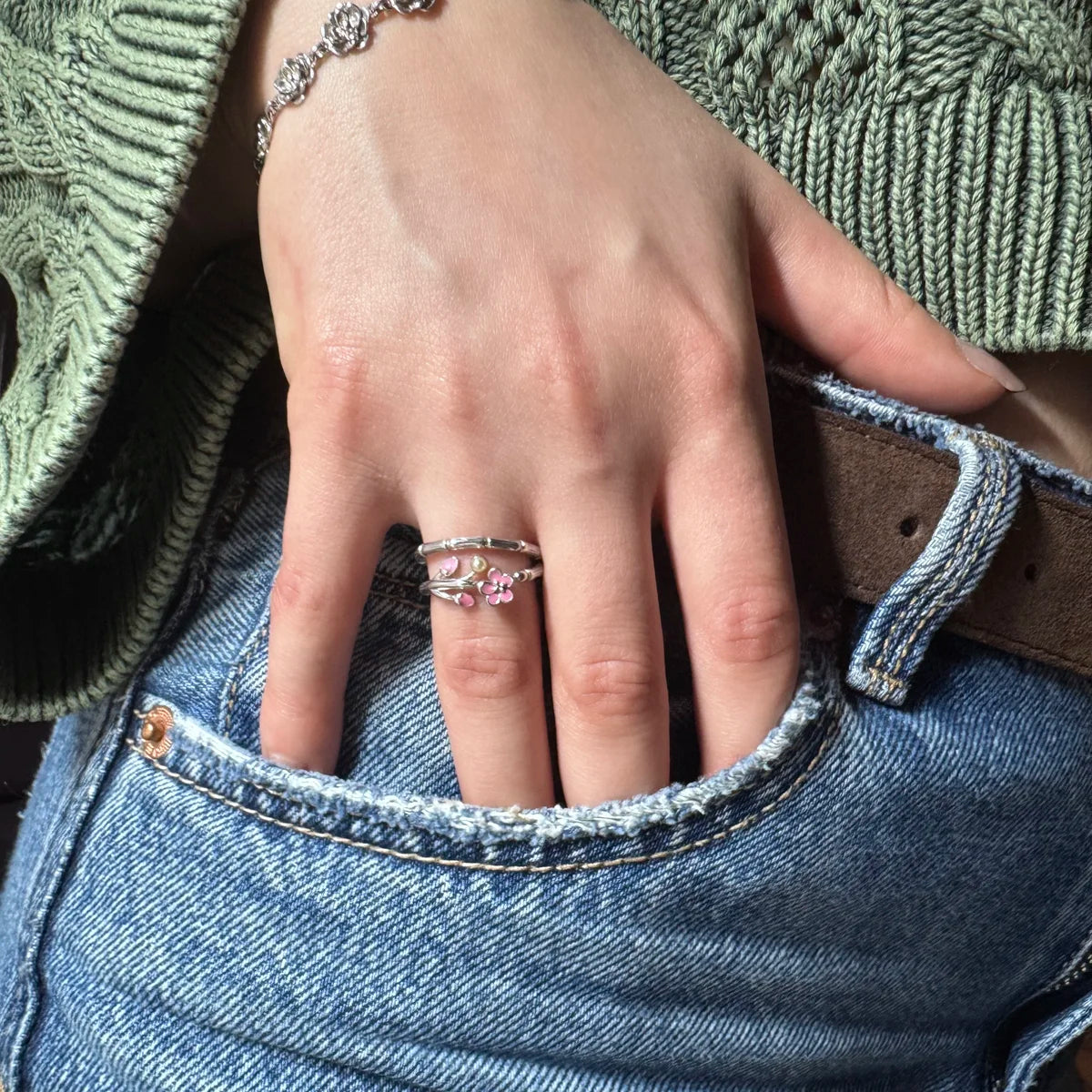 Bague fleur argent Hanami portée au doigt, main de femme dans une poche de jean décontractée