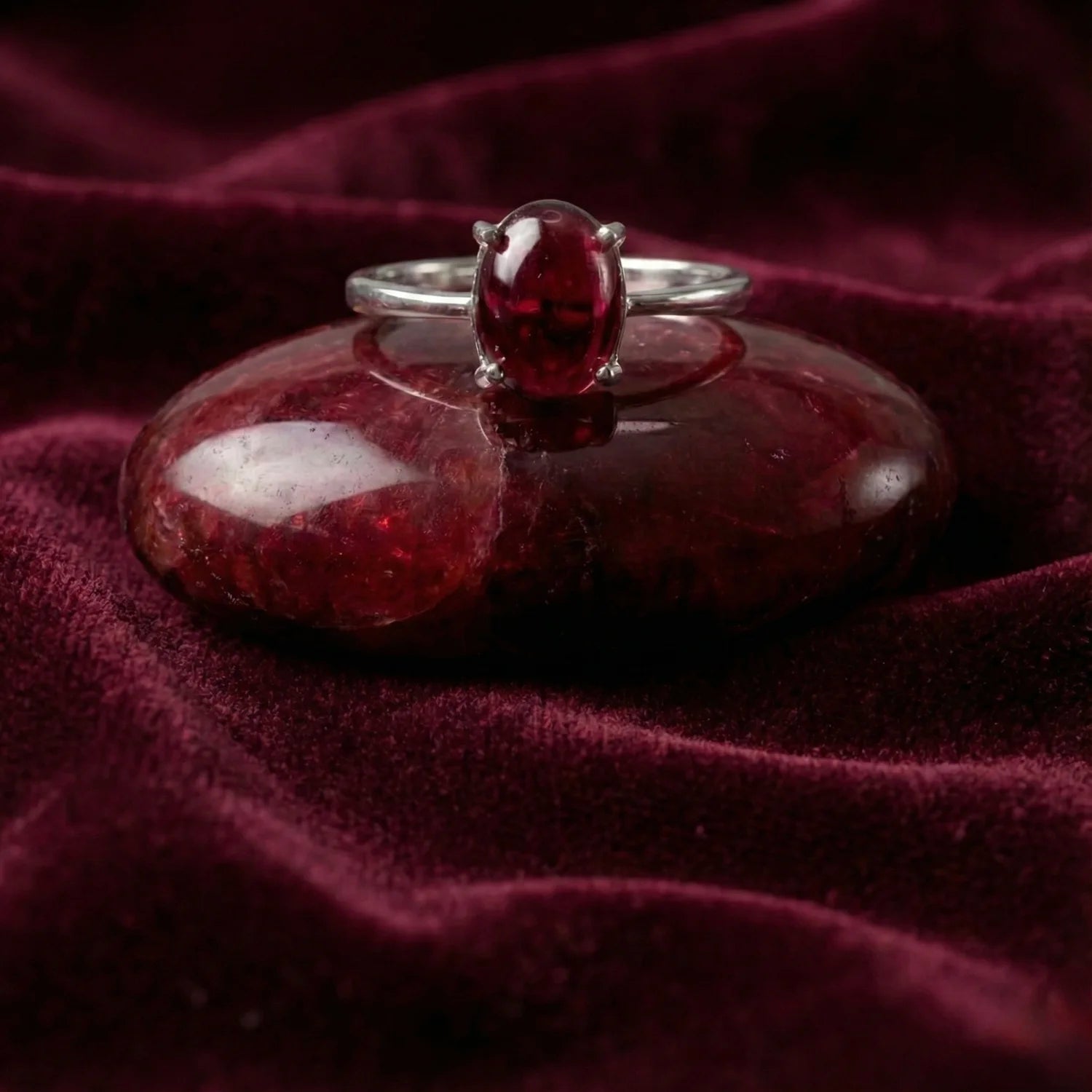 Bague Aura Pourpre posée sur du un galet grenat rouge, ambiance lithothérapie ancrage.