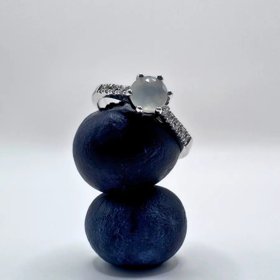 Une bague pierre de lune posée sur 2 myrtilles empilées