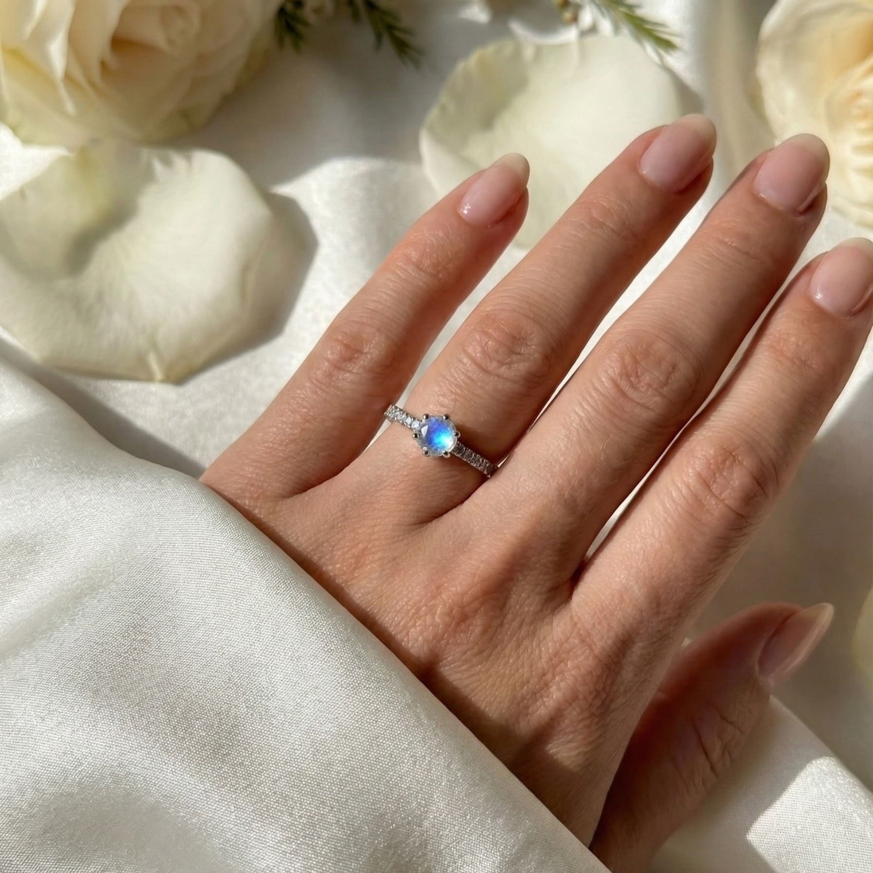 Main de femme portant une bague solitaire Pierre de Lune, symbole de féminité et d'intuition.