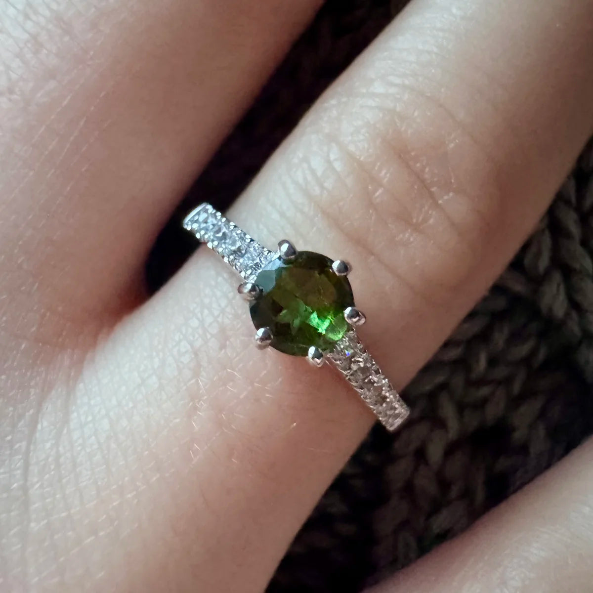 Gros plan sur la Tourmaline verte d'une bague solitaire, pierre de renouveau aux reflets profonds.
