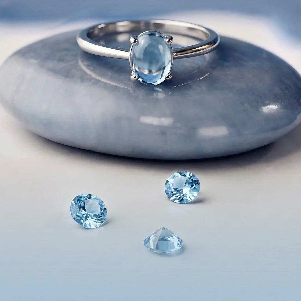 Bague topaze bleue posée sur un galet, fond blanc ou naturel. Bague idéale en lithothérapie.