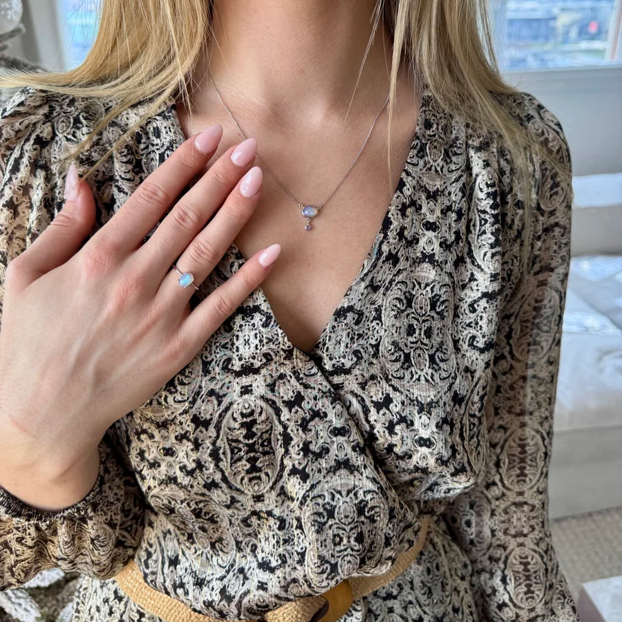 Bague solitaire en argent rhodié ornée d'une opale véritable taille cabochon aux reflets arc-en-ciel.