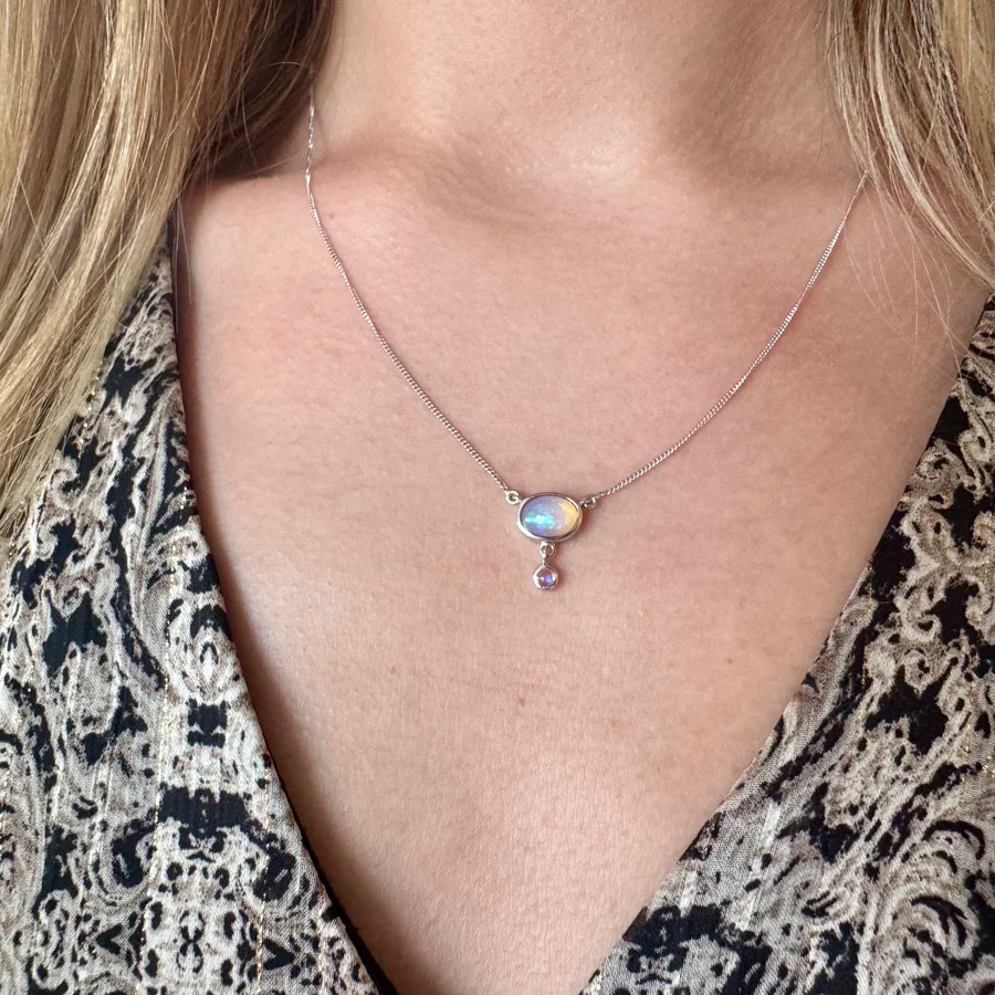 Collier fin en argent 925 avec pendentif opale aux reflets bleutés porté au cou. Modèle Sillage Lunaire.
