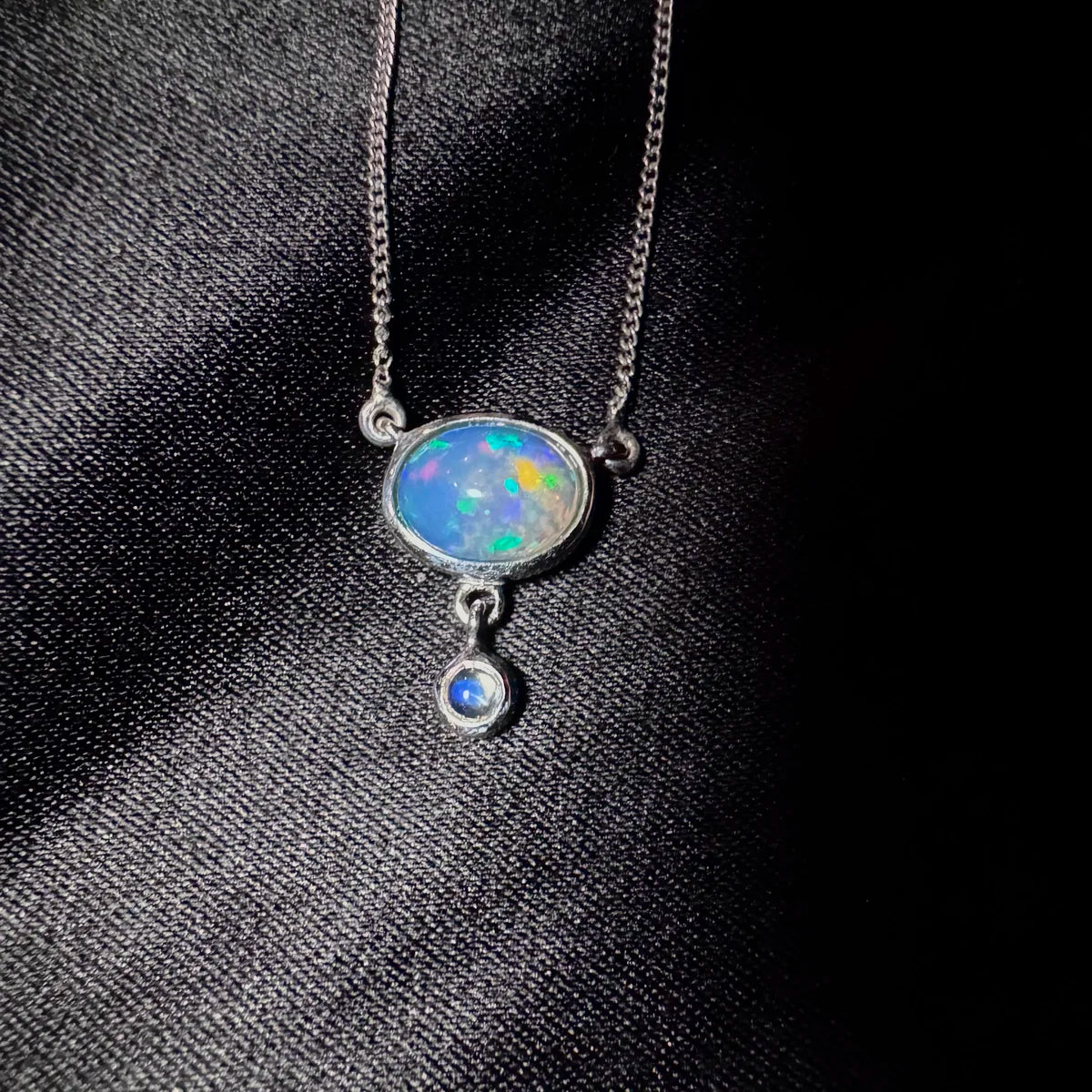 Collier opale photographié sur fond noir révélant l'intensité des feux multicolores et l'éclat de la pierre.