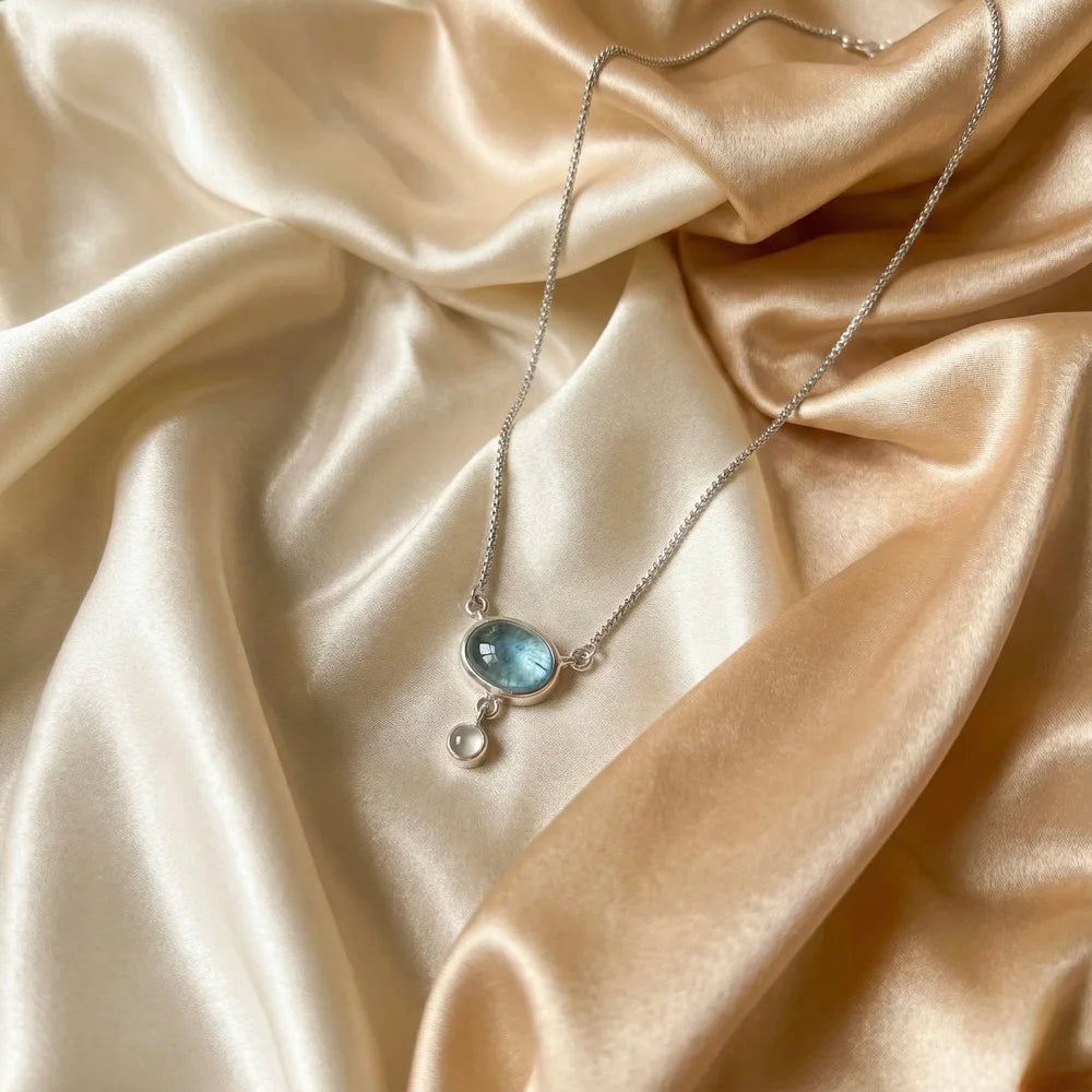 Détail de la topaze bleue naturelle véritable et de la perle de lune protectrice sur argent rhodié.