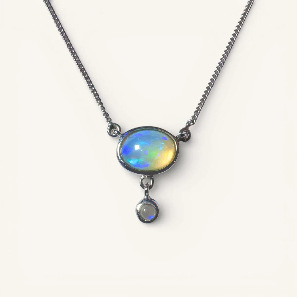 Gros plan sur le collier en opale éthiopienne et sa petite pierre satellite. Monture en argent sterling 925