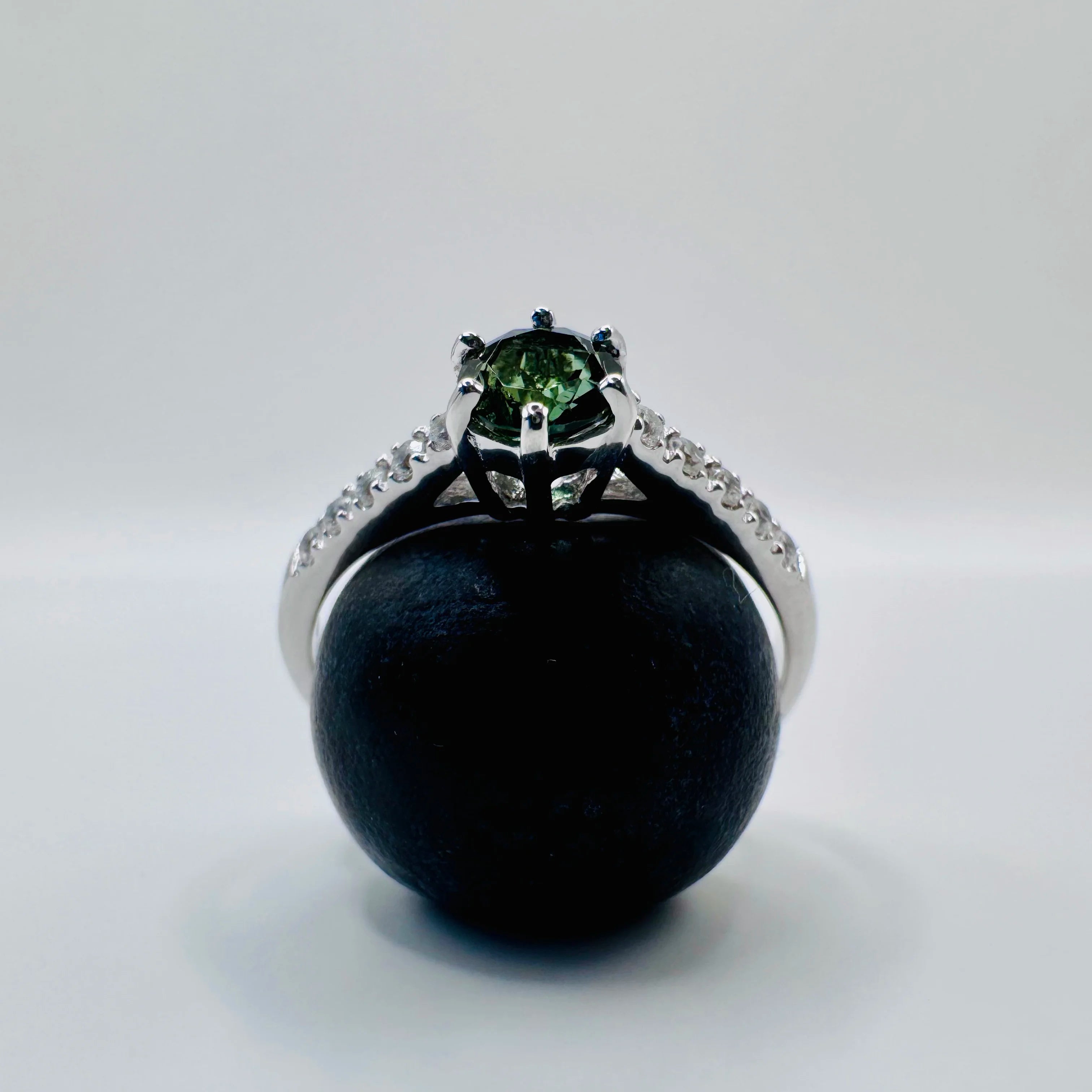 Profil d'une bague solitaire femme en argent, monture délicate présentée sur une myrtille mettant en valeur la Tourmaline verte